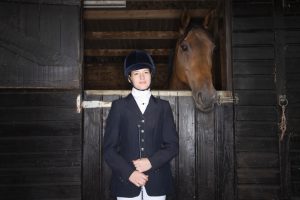 Portrait of Female horseback rider with horse in stable